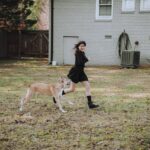 A joyful moment outdoors featuring a woman running with a dog in a backyard.