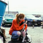 a woman in an orange sweater petting a dog